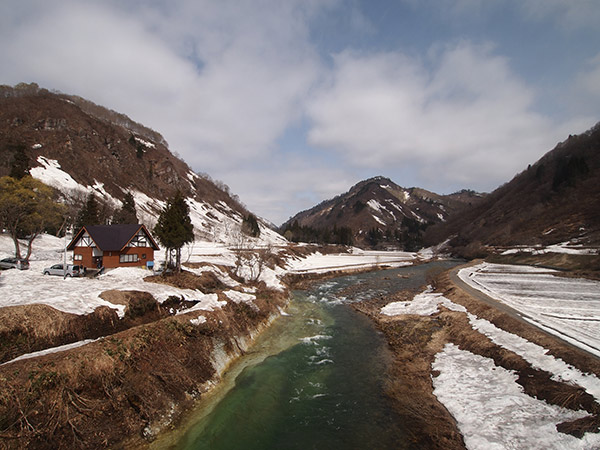 残雪の中を川が流れる